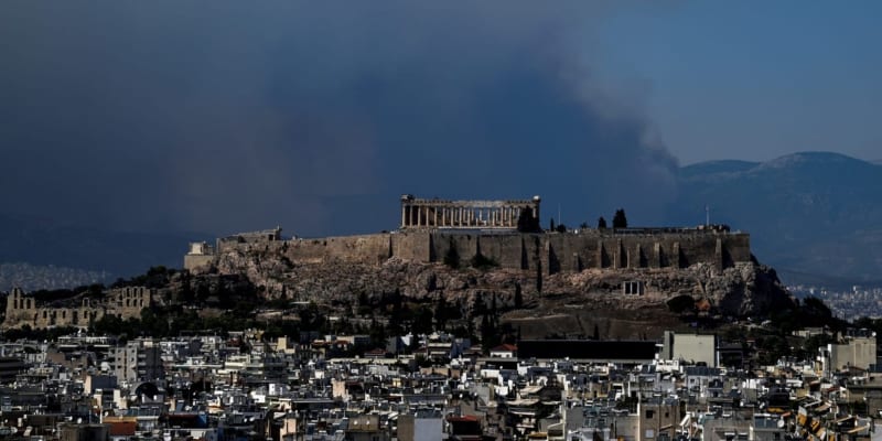 Dým se valí za starověkým chrámem Parthenon na vrcholu kopce Akropole, když na předměstí Atén 22. srpna 2023 zuří lesní požár. 