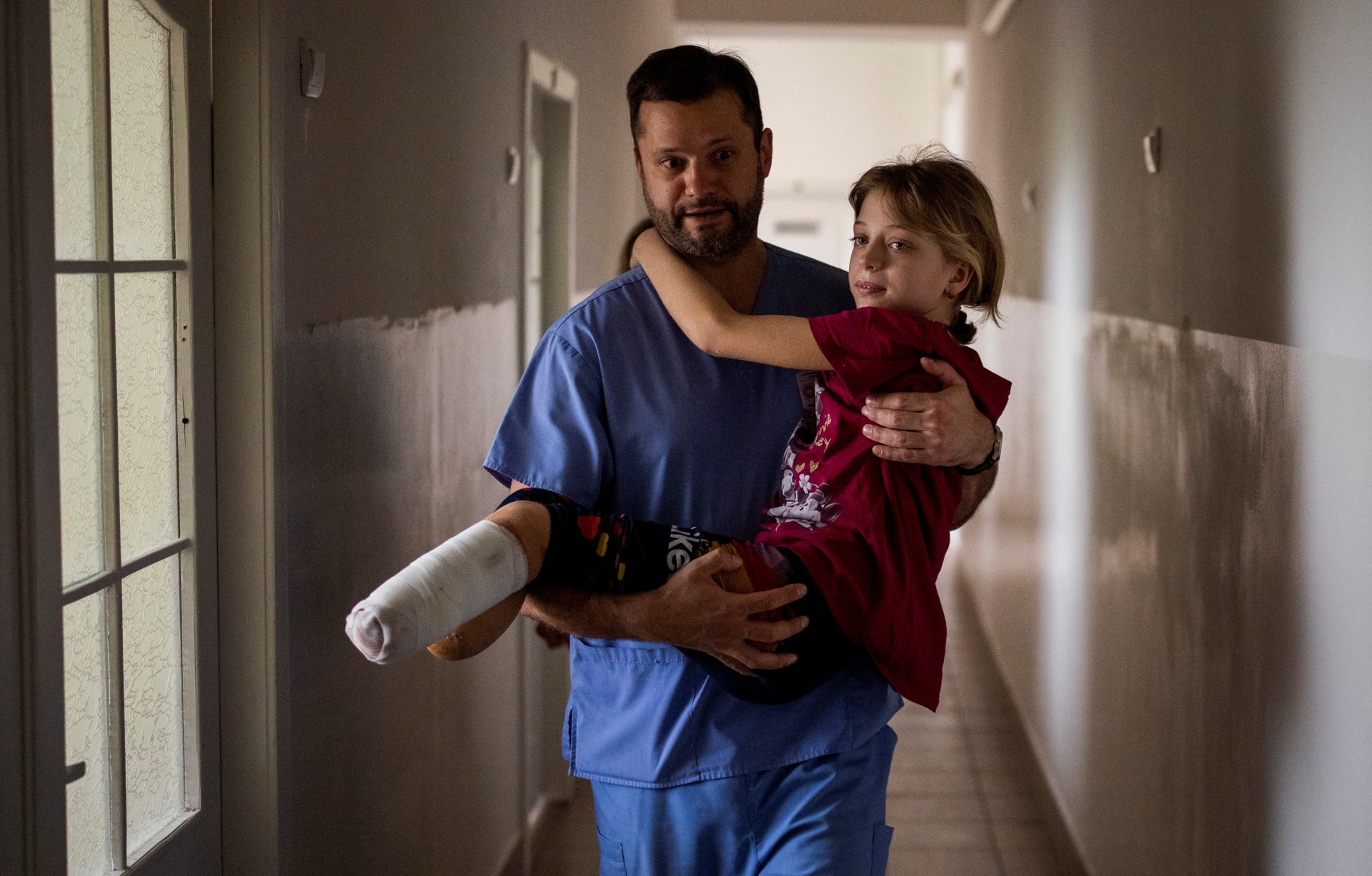 Lékař přenáší ukrajinskou dívku zmrzačenou po ruském útoku.