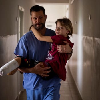 Lékař přenáší ukrajinskou dívku zmrzačenou po ruském útoku.
