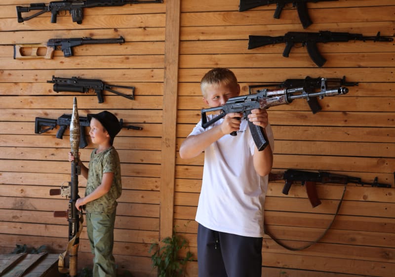 Chlapci si zkouší zbraně na přehlídce u příležitosti Dne ruských vzdušných sil (12. 8. 2023).