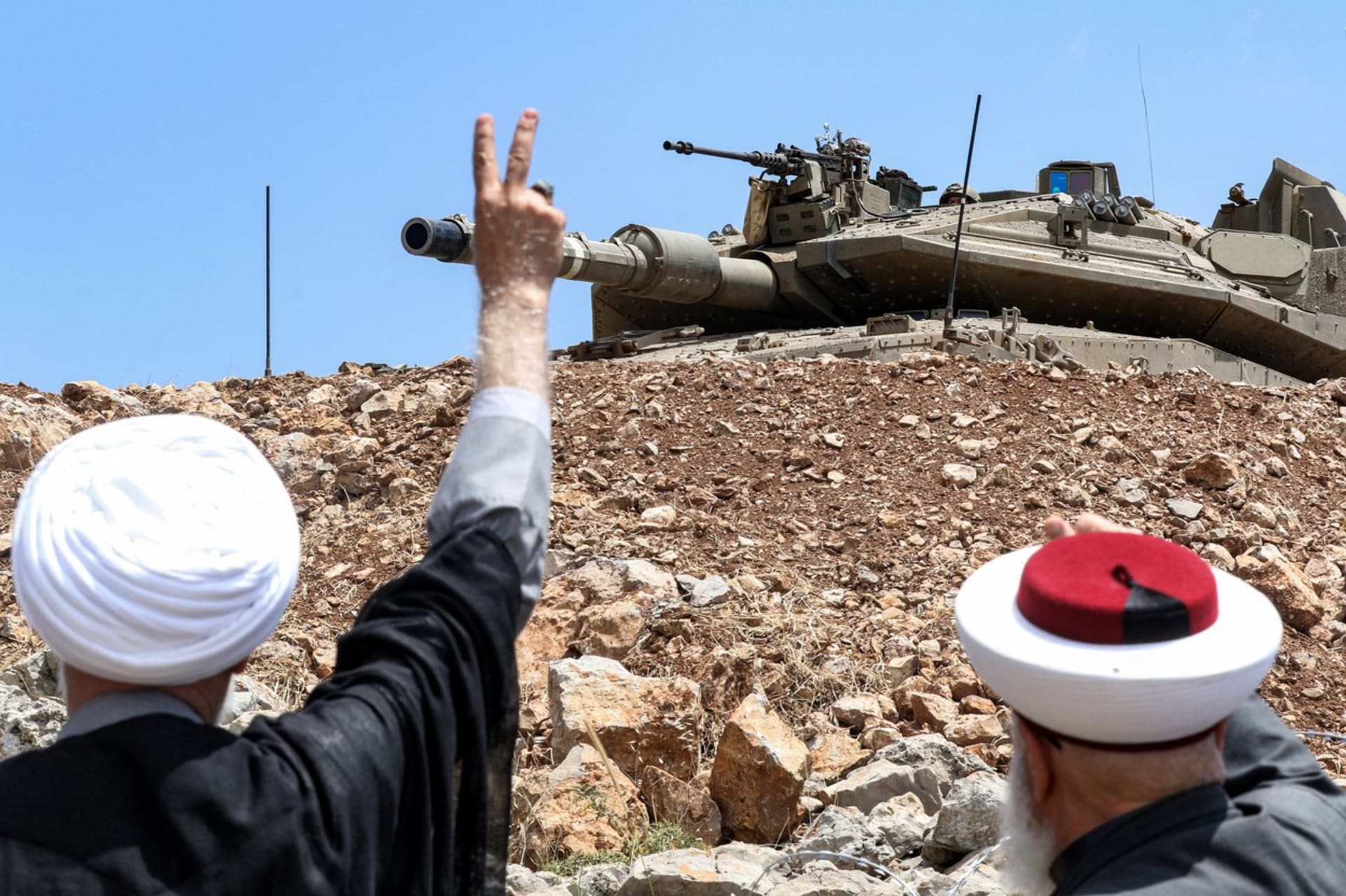 Libanonští muslimští duchovní gestikulují směrem k izraelskému tanku Merkava