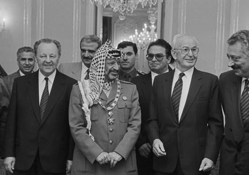 Návštěva Jásira Arafata v Praze, 18. října 1989. Do Československa tehdy přijel i Bassam Abu Sharif (s brýlemi za Husákem), podle amerického časopisu Time nejznámější tvář palestinského teroru. Prezident ČSSR Gustáv Husák předal na Pražském hradě předsedovi výkonného výboru OOP Jásiru Arafatovi Československý řád Bílého lva I. třídy.