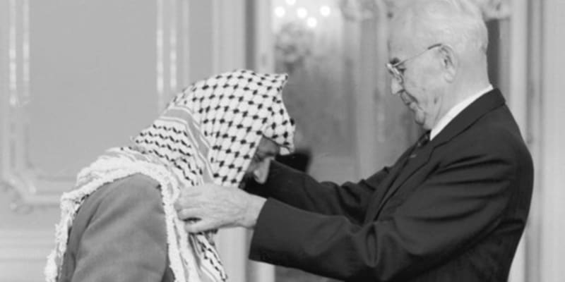 Návštěva Jásira Arafata v Praze, 18. října 1989. Do Československa tehdy přijel i Bassam Abu Sharif, podle amerického časopisu Time nejznámější tvář palestinského teroru. Prezident ČSSR Gustáv Husák (vpravo) předal na Pražském hradě předsedovi výkonného výboru OOP Jásiru Arafatovi Československý řád Bílého lva I. třídy.