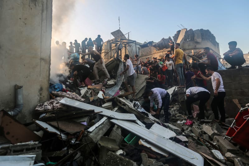 Lidé prohledávají trosky budov ve městě Chán Junís po útoku Izraele.