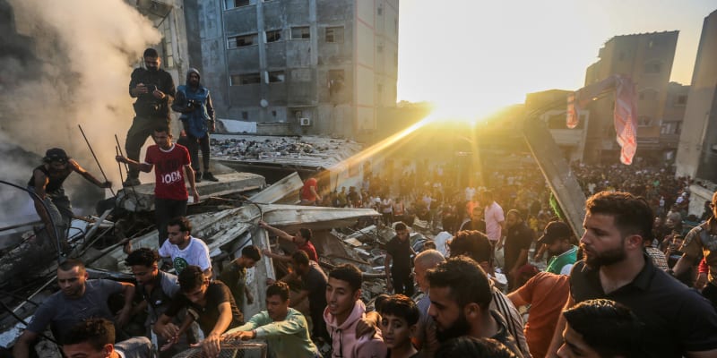 Lidé prohledávají trosky budov ve městě Chán Junís po útoku Izraele.