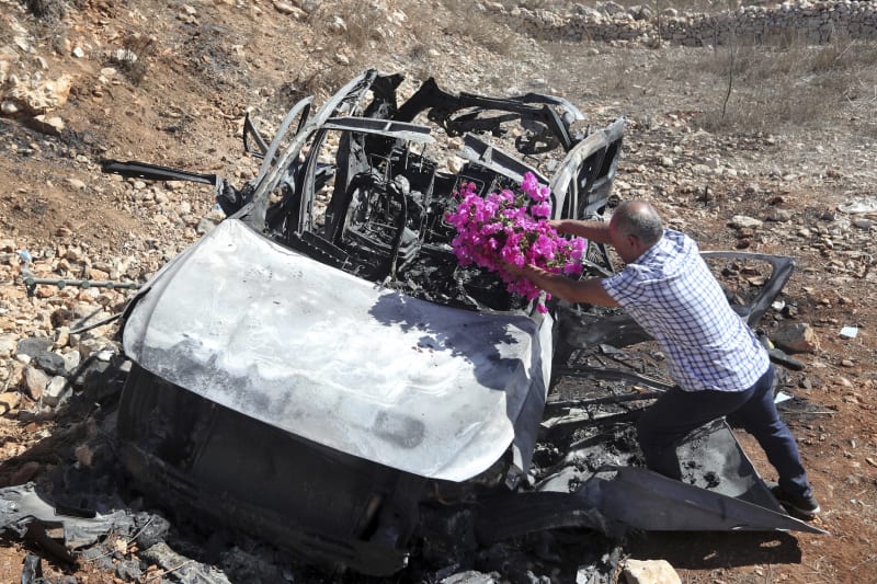 Strýc ří dětí, které zemřely po izraelském útoku v jižním Libanonu pokládá kytici na auto, ve kterém spolu se svoji matkou cestovaly