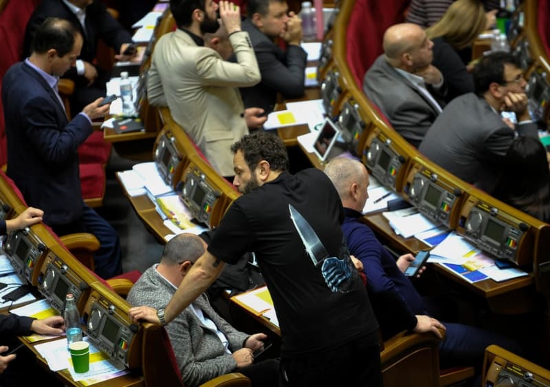 Ukrajinský poslanec za stranu Sluha národa prezidenta Volodymyra Zelenského, Oleksandr Dubinskyj (s tričkem s nožem za zády), čelí stíhání kvůli zradě.