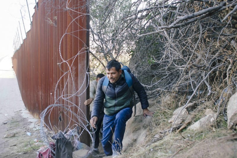 Migranti pronikají z Mexika do Kalifornie mezerou ve zdi.