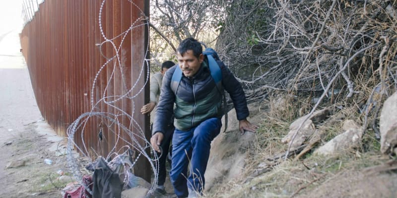 Migranti pronikají z Mexika do Kalifornie mezerou ve zdi.
