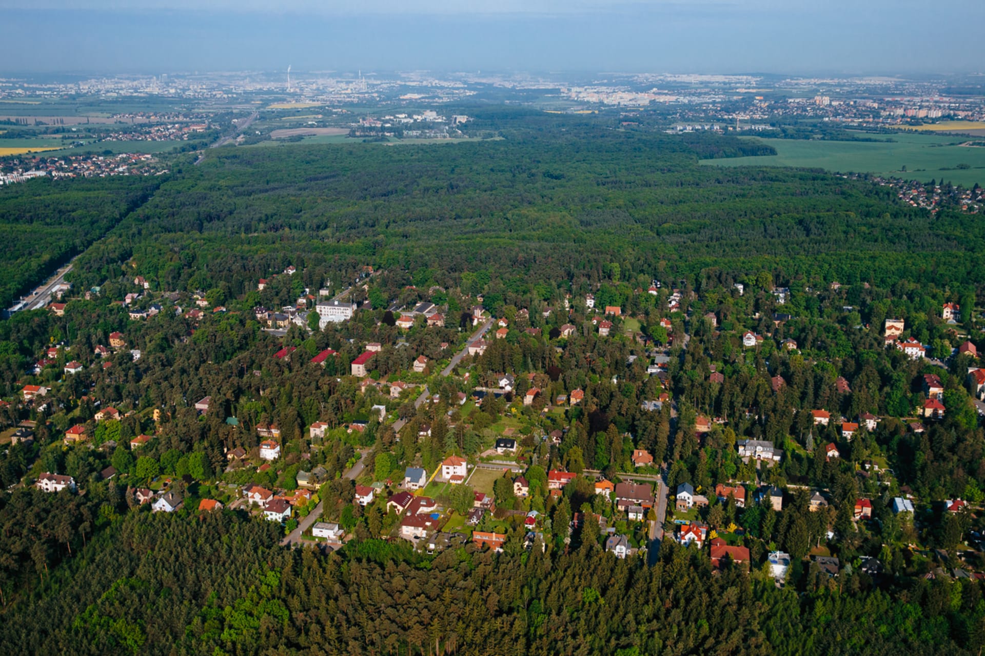 Letecký pohled na část Klánovic zanořenou do Klánovického lesa