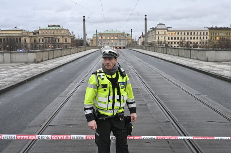 Policista hlídkuje u uzavřeného Mánesova mostu směřujícího k nám. Jana Palacha, kde se v budově Filozofické fakulty střílelo, 21. prosince 2023, Praha