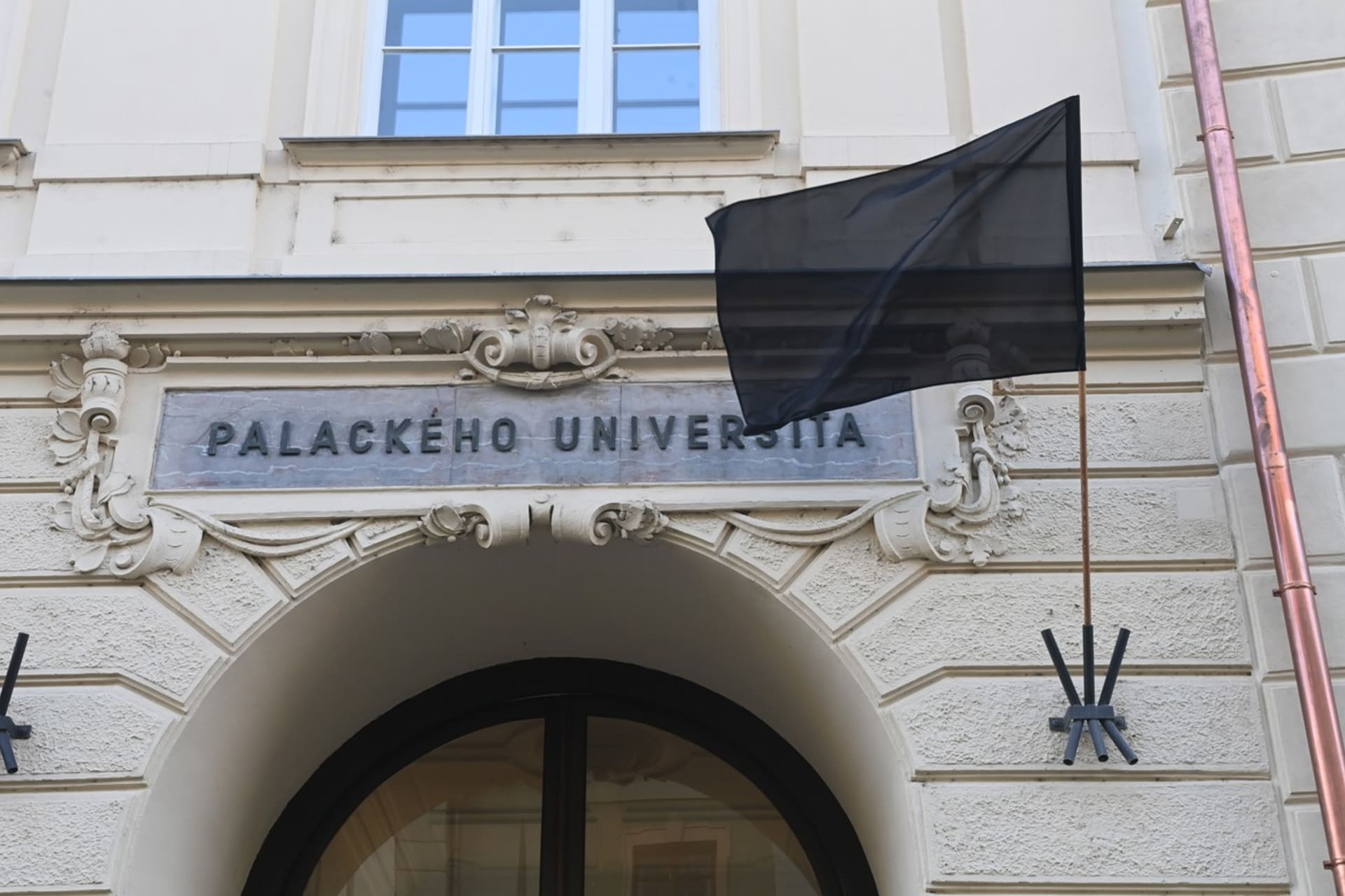 Lidé zapalují svíčky na pietním místě před budovou Filozofické fakulty Univerzity Palackého v Olomouci.