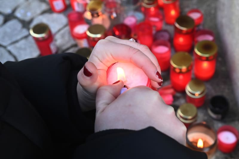 Lidé zapalují svíčky na pietním místě před budovou Filozofické fakulty Univerzity Palackého v Olomouci.