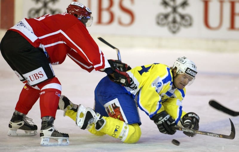 Kanadský hráč Reggie Savage sráží na led českého útočníka HC Davos Josefa Marhu v utkání Spenglerova poháru.