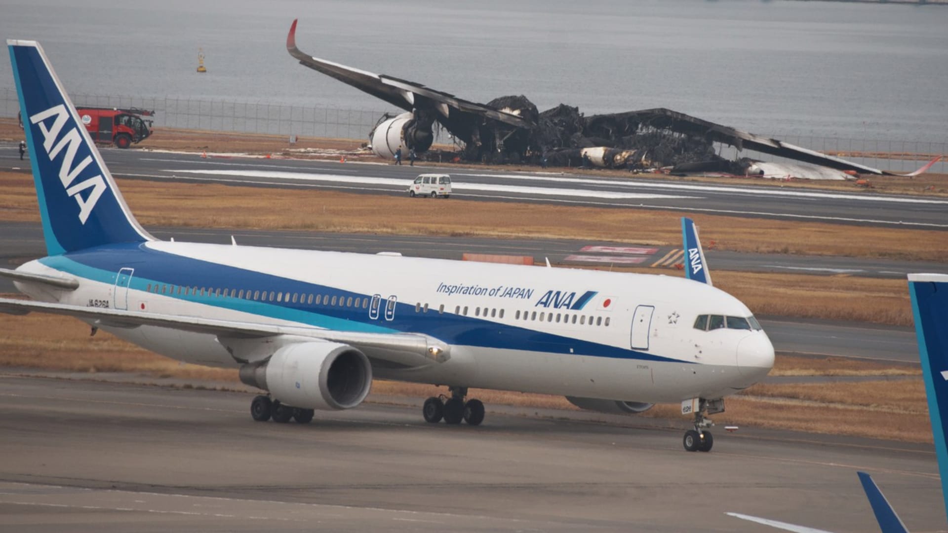 Zbytky ohořelého letounu na tokijském letišti Haneda a před ním funkční stroj.