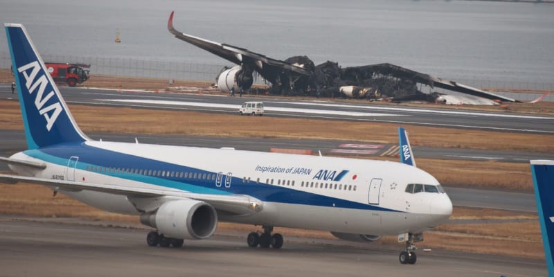 Zbytky ohořelého letounu na tokijském letišti Haneda a před ním funkční stroj.