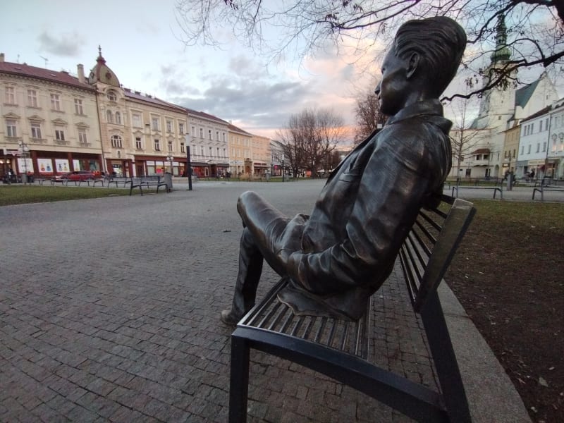 Bronzový básník Jiří Wolker na náměstí v Prostějově. Upřeně se dívá na rodný dům, ve kterém i zemřel, a z něhož v sobotu 5. ledna 1924 také vyšel pohřební průvod s básníkovou rakví. 