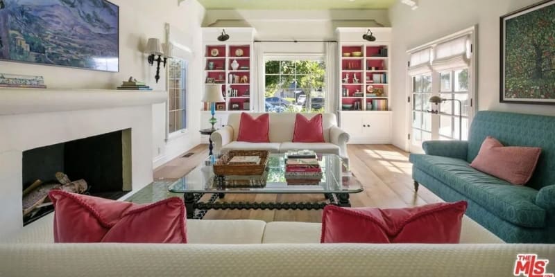 Herečka Emma Stone prodává dům v Los Angeles: Otevřený obývací pokoj domu má barevnou estetiku. Jeho bílé stěny a podlahy z tvrdého dřeva zdobí modrozelený gauč, růžové polštáře a výrazná umělecká díla.
