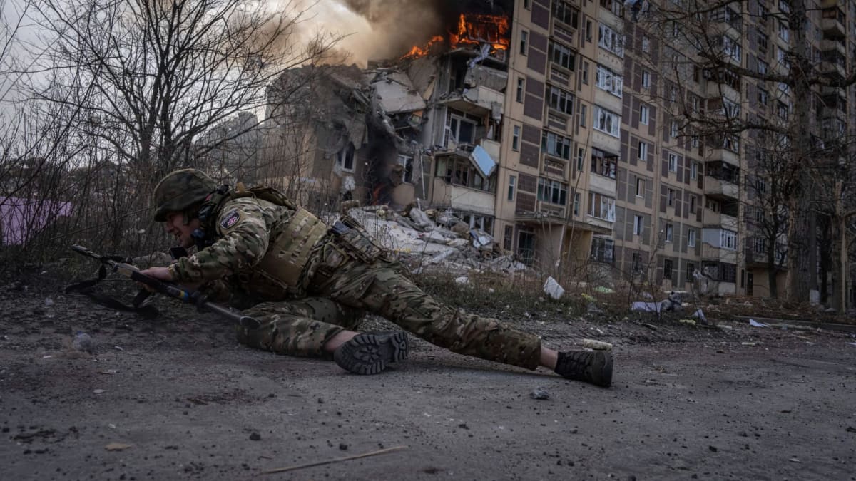 Ukrajinský voják se kryje v Avdijivce po ruském útoku.