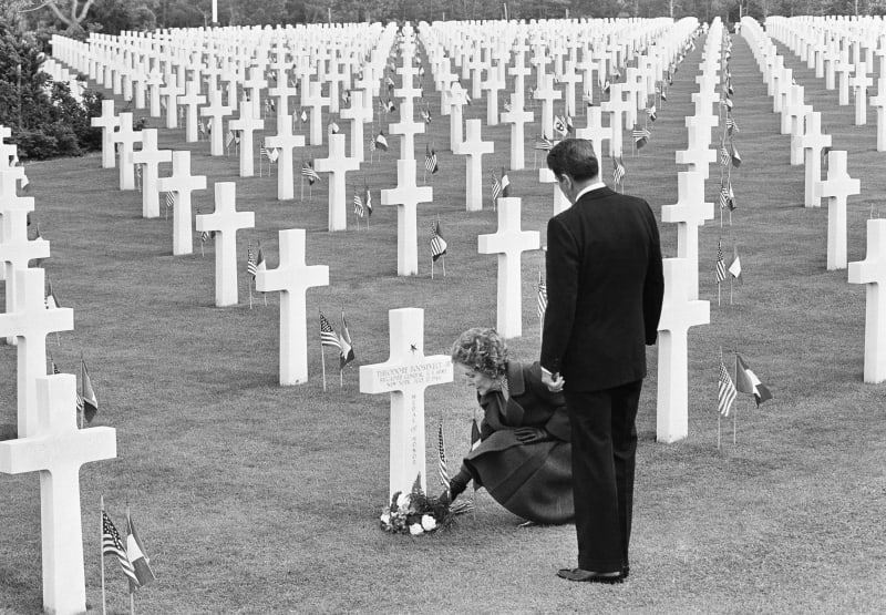 Americký prezident Ronald Reagan stojí vedle první dámy Nancy Reaganové, která pokládá květiny k hrobu brigádního generála z druhé světové války Theodora Roosevelta mladšího na americkém hřbitově v Normandii.