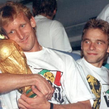 Německý fotbalový reprezentant Andreas Brehme s mistrovským pohárem a jeho spoluhráč Thomas Haessler v italském Římě (9. červenec 1990)
