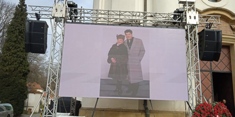 Na plátně před kostelem se promítají fotografie ze života Olgy Kočkové.