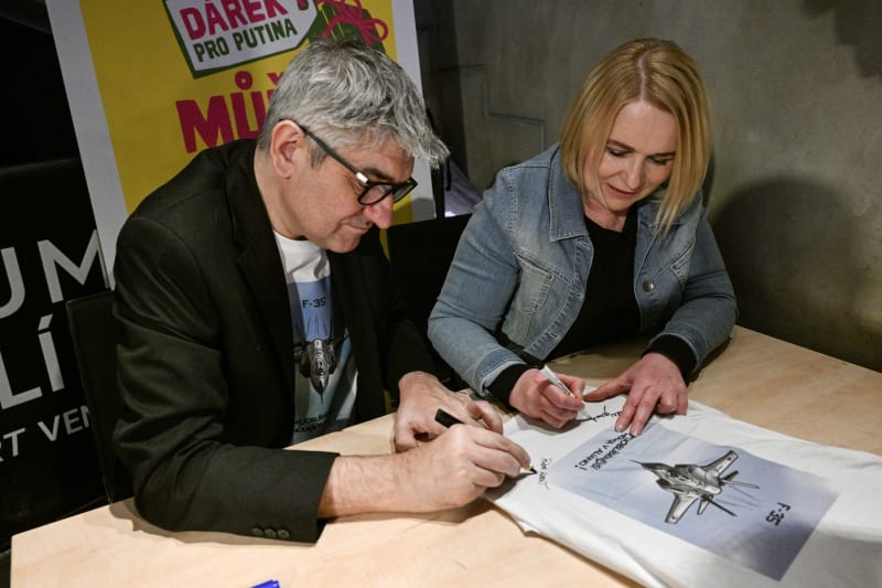 Ministryně obrany Jana Černochová (ODS) a kreslíř Štěpán Mareš podepisují trička na koncertu (24. 2. 2024).