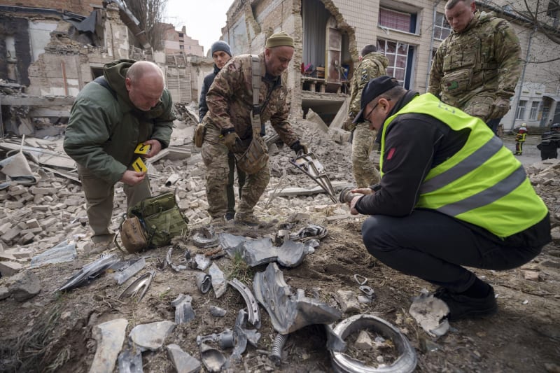 Ukrajinští vojenští experti sbírají zbytky rakety u zničené budovy v Kyjevě, Ukrajina, pondělí 25. března 2024. 