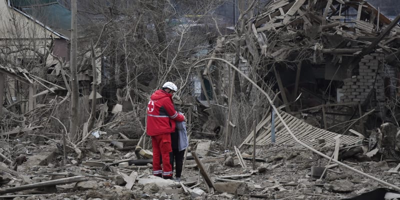 Zdravotník utěšuje ženu na místě ruského leteckého útoku v Záporoží na Ukrajině v pátek 22. března 2024. 