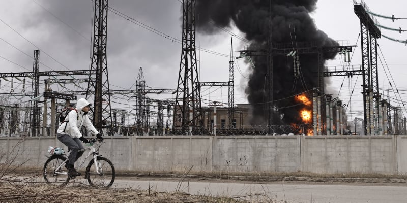 Muž projíždí na kole kolem elektrárny po ruském útoku v Charkově.