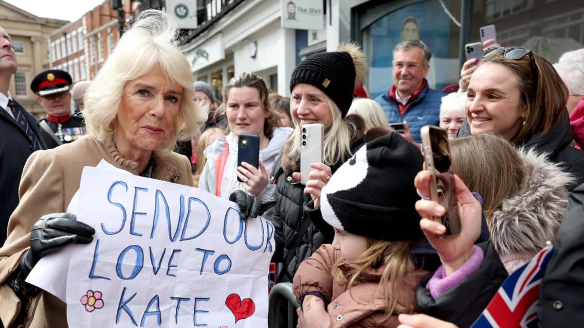 Britská královna Camilla drží transparent s nápisem: „Posíláme naši lásku Kate“. 